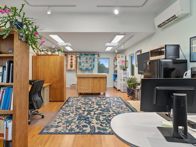 home office featuring light wood-type flooring, rail lighting, and a wall unit AC