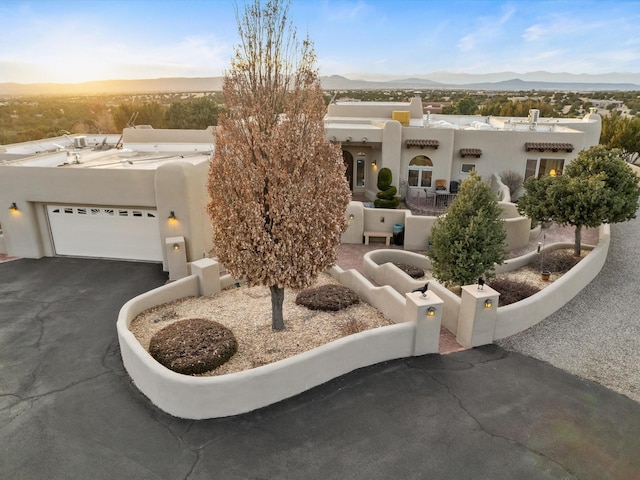 pueblo revival-style home featuring aphalt driveway, a mountain view, and stucco siding