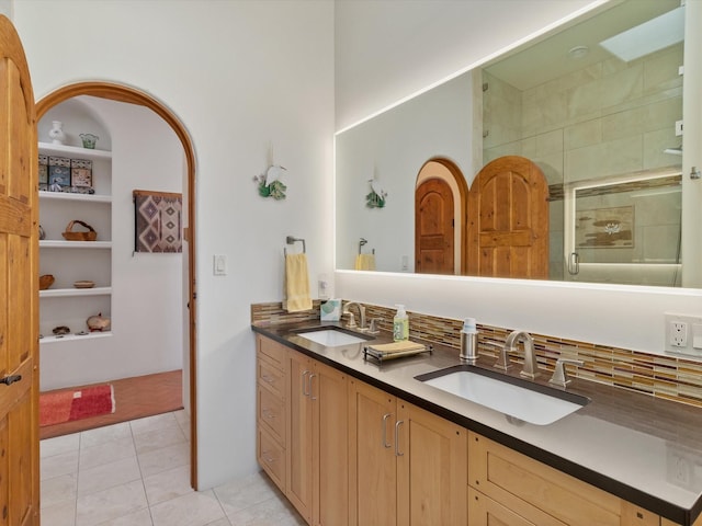 bathroom featuring tile patterned floors, a stall shower, double vanity, and a sink