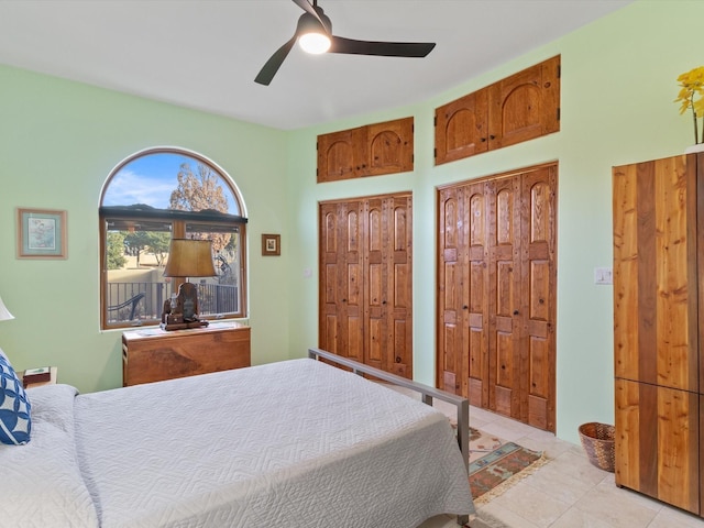 bedroom with light tile patterned floors, a ceiling fan, and multiple closets