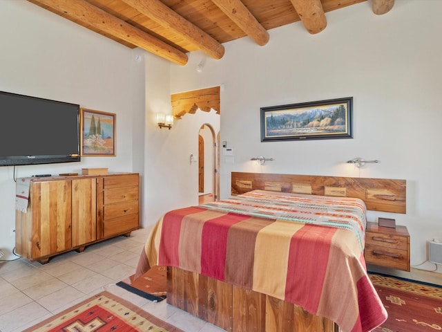 bedroom with wooden ceiling, light tile patterned flooring, arched walkways, and beam ceiling