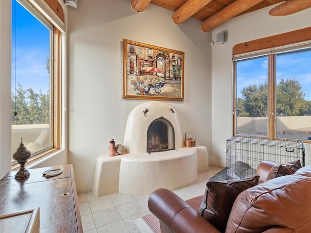 living room with light tile patterned floors, beamed ceiling, a healthy amount of sunlight, and a warm lit fireplace