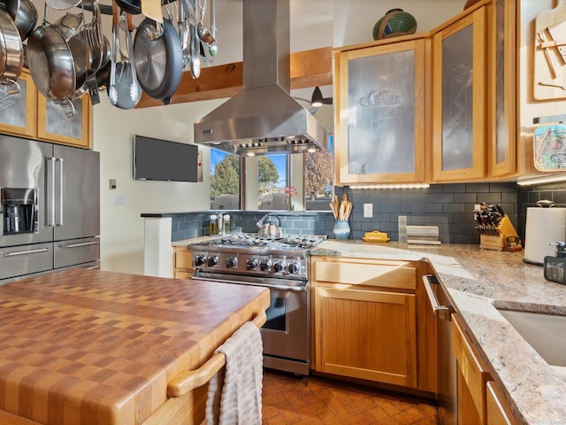 kitchen with high end appliances, island exhaust hood, tasteful backsplash, and butcher block countertops