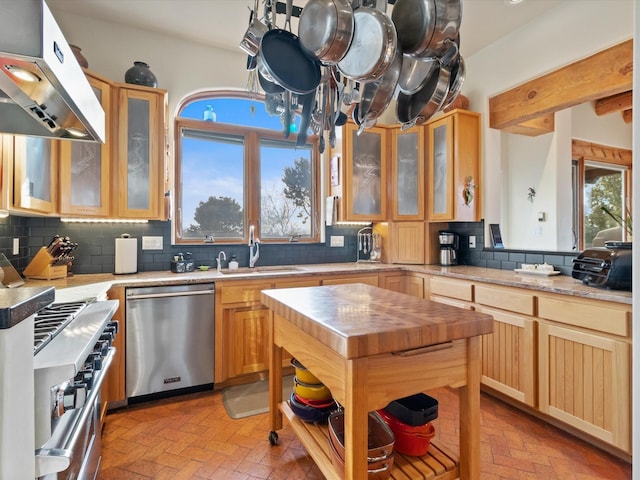 kitchen with under cabinet range hood, a sink, backsplash, stainless steel appliances, and butcher block counters