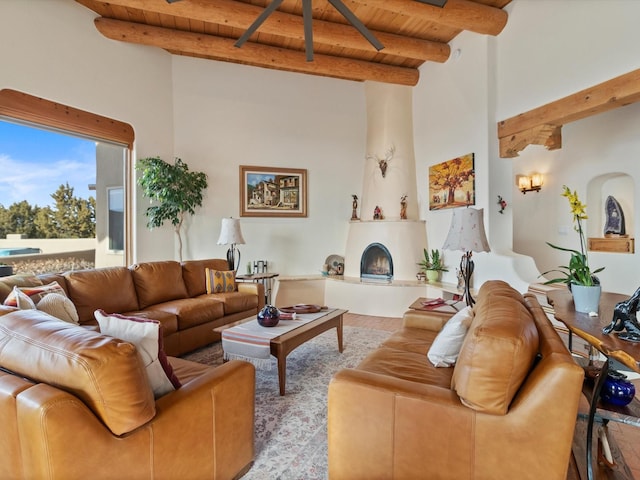 living area featuring beamed ceiling, a large fireplace, arched walkways, wooden ceiling, and a towering ceiling