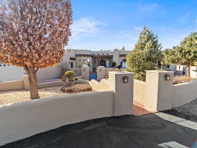 adobe home featuring a gate, a fenced front yard, and stucco siding