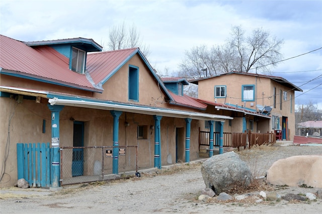 exterior space featuring metal roof, covered porch, and stucco siding