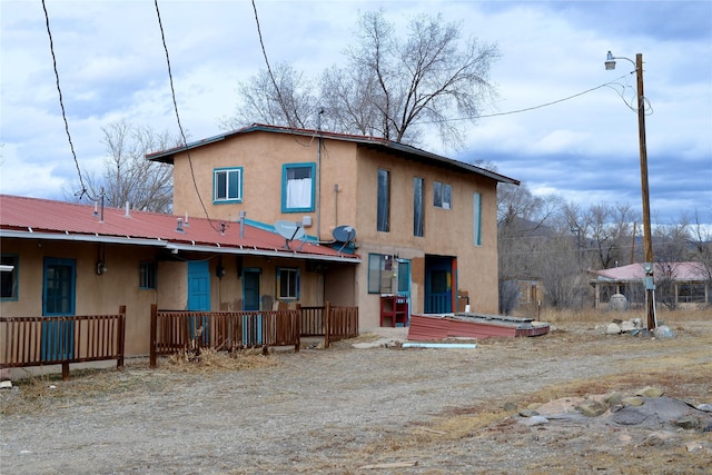 back of property with metal roof and stucco siding