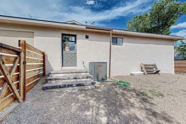 back of property with entry steps, fence, and stucco siding