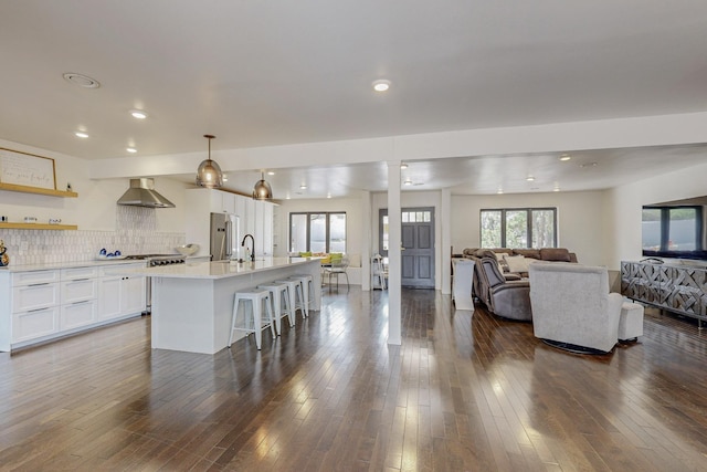 kitchen with dark wood finished floors, open floor plan, and wall chimney range hood