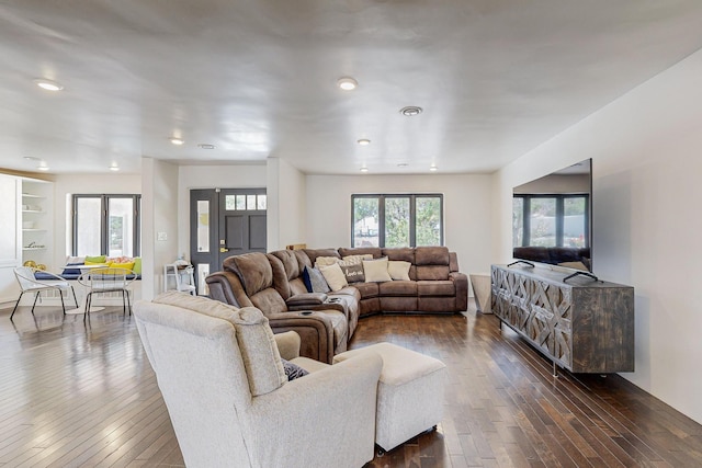 living room with built in shelves and dark wood-style floors