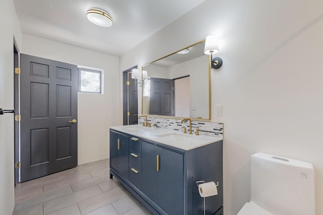 bathroom featuring decorative backsplash, double vanity, toilet, and a sink