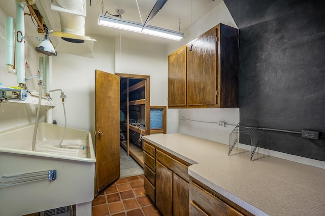 kitchen with light countertops, dark tile patterned flooring, and brown cabinets