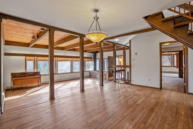 interior space with beamed ceiling, baseboards, hardwood / wood-style floors, and stairs