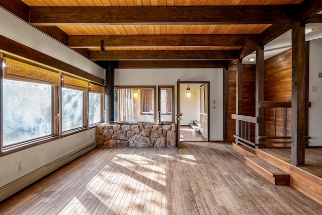 unfurnished living room featuring a baseboard heating unit, beam ceiling, and hardwood / wood-style floors