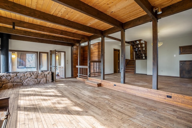 unfurnished living room with beam ceiling, stairs, and wood-type flooring