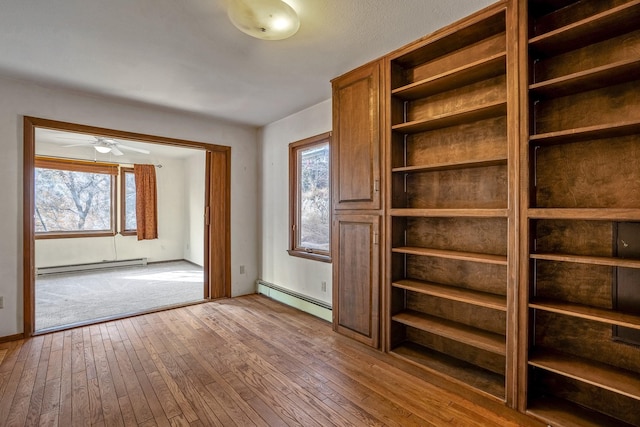 unfurnished bedroom with hardwood / wood-style flooring, a baseboard heating unit, and a baseboard radiator