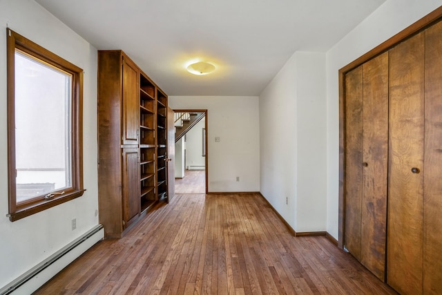 interior space featuring hardwood / wood-style floors, baseboards, a closet, and a baseboard radiator