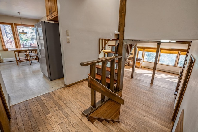 dining space with a wealth of natural light, stairway, baseboards, and light wood-style floors