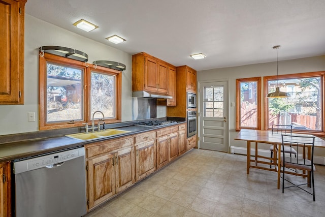 kitchen featuring dark countertops, under cabinet range hood, light floors, appliances with stainless steel finishes, and a sink