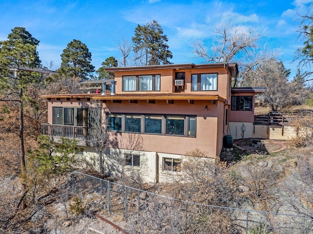 rear view of property with stucco siding and fence