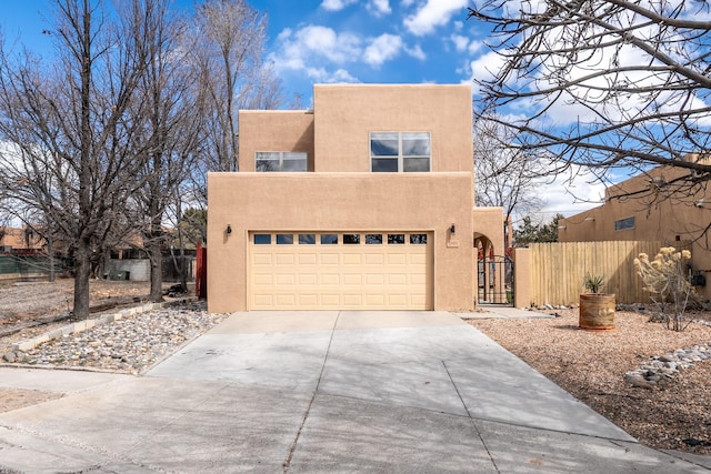 pueblo-style home with a gate, fence, driveway, stucco siding, and a garage