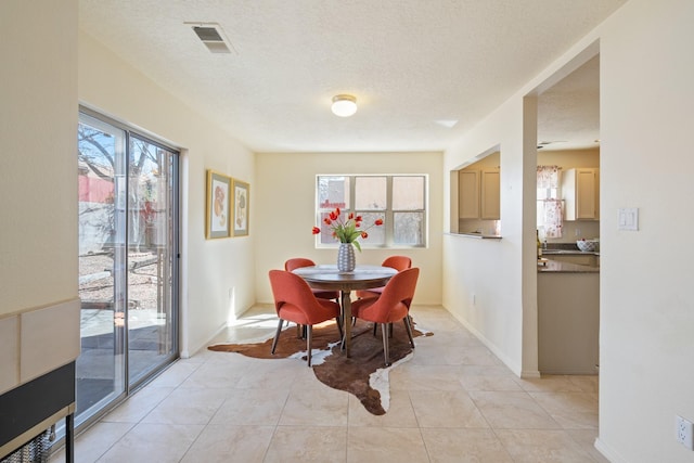 dining area featuring light tile patterned floors, baseboards, visible vents, and a textured ceiling