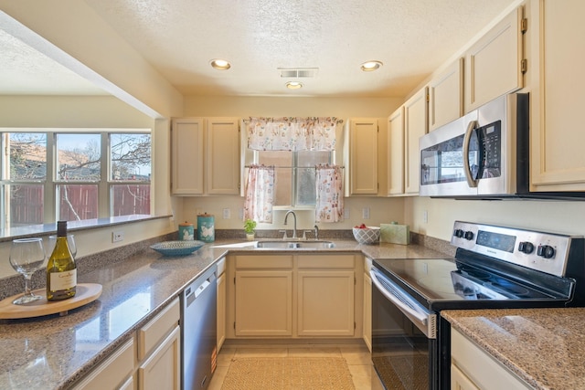 kitchen featuring light stone counters, recessed lighting, a sink, appliances with stainless steel finishes, and a textured ceiling