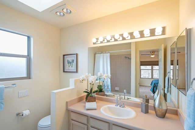 full bath with curtained shower, toilet, a skylight, and vanity