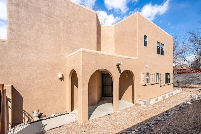 back of property featuring stucco siding and fence