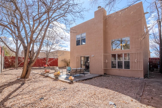 back of property featuring a patio area, stucco siding, a fenced backyard, and a chimney