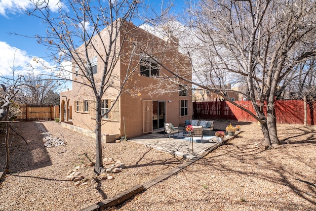 back of house featuring outdoor lounge area, a patio, a fenced backyard, and stucco siding