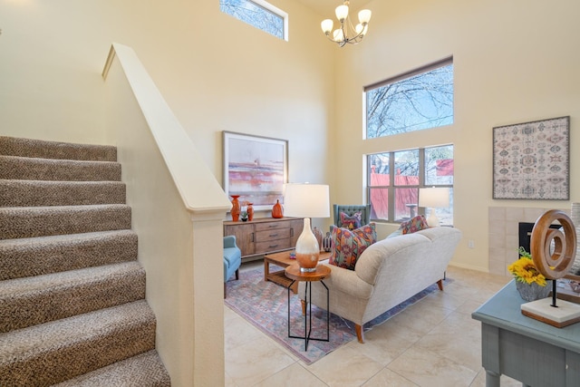 living room with a wealth of natural light, stairway, an inviting chandelier, and a towering ceiling