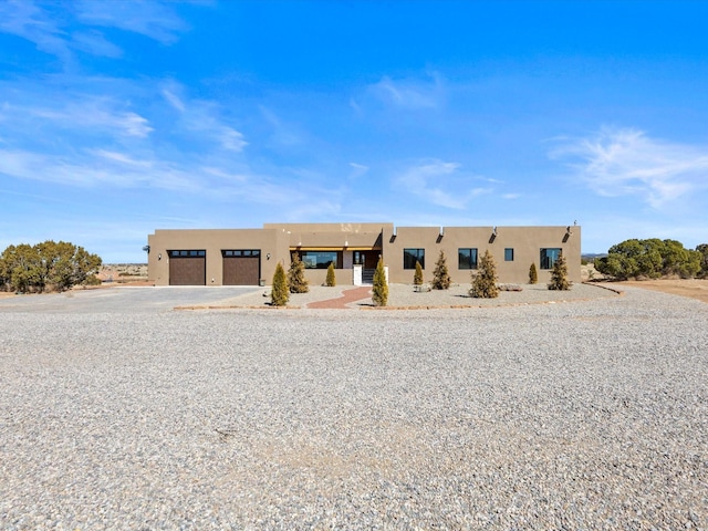 pueblo revival-style home with stucco siding and an attached garage