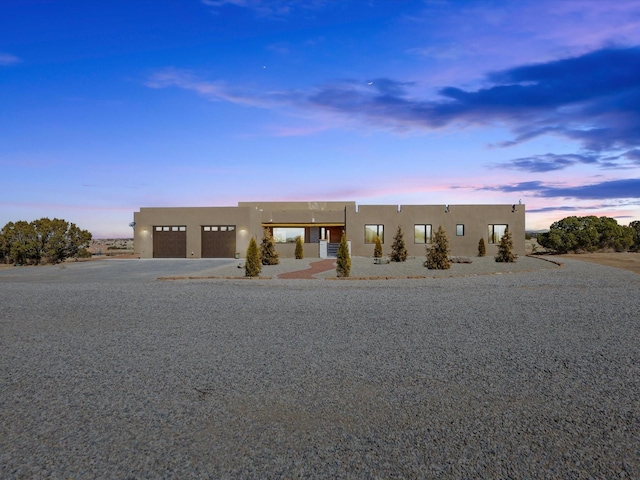 pueblo-style home with a garage, driveway, and stucco siding