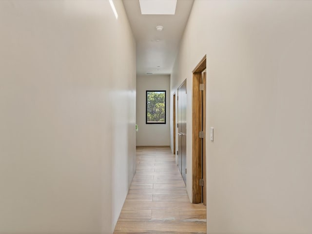 hall featuring light wood finished floors and a skylight