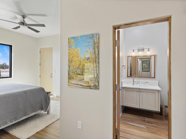 bedroom with a sink, ensuite bath, and wood finished floors