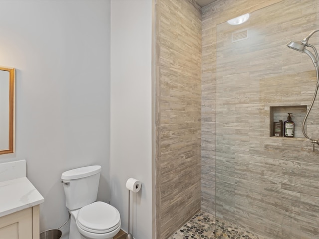 full bath featuring a tile shower, toilet, and vanity