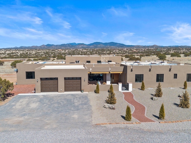 southwest-style home featuring an attached garage, a mountain view, driveway, and stucco siding