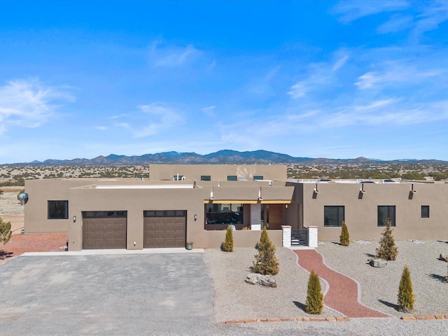 southwest-style home featuring stucco siding, a mountain view, driveway, and a garage