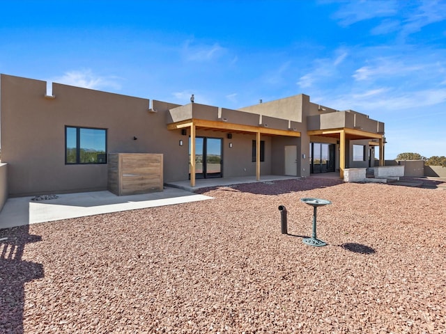 rear view of house featuring a patio area and stucco siding