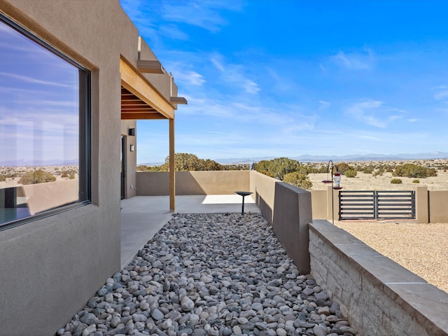 view of yard featuring a mountain view, a patio, a balcony, and fence