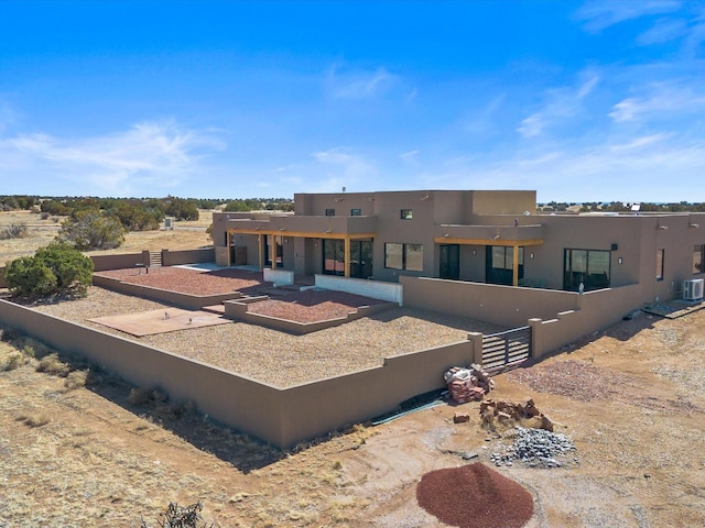 back of house with central air condition unit, fence, and stucco siding