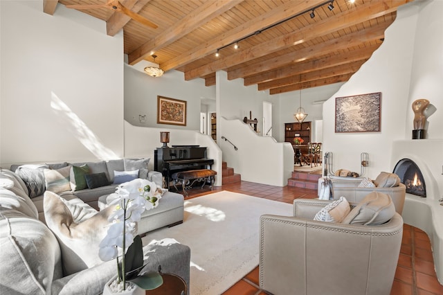 living room with stairway, beam ceiling, a lit fireplace, tile patterned flooring, and wooden ceiling