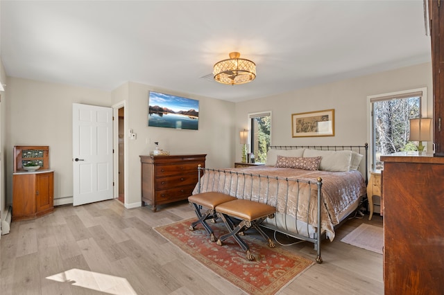 bedroom featuring light wood-style flooring, baseboards, and baseboard heating