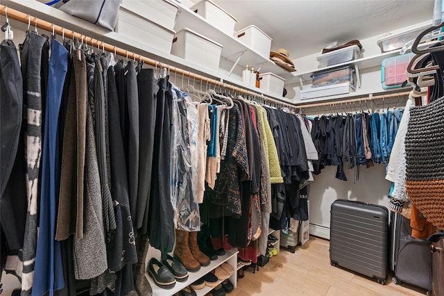 walk in closet with baseboard heating and wood finished floors