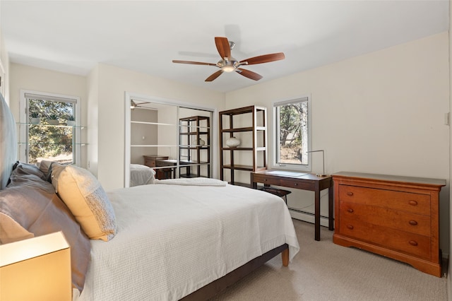 carpeted bedroom with a baseboard heating unit and a ceiling fan