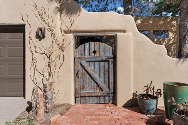 property entrance featuring a garage, stucco siding, and a gate