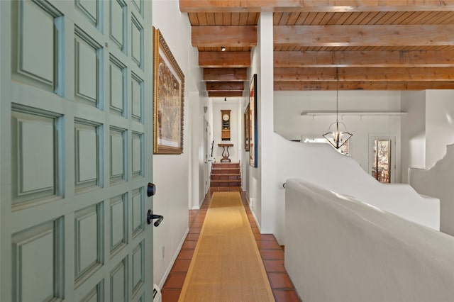 hallway with beamed ceiling, an inviting chandelier, baseboards, wood ceiling, and stairs