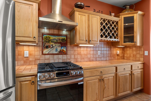 kitchen featuring glass insert cabinets, butcher block counters, decorative backsplash, exhaust hood, and stainless steel appliances